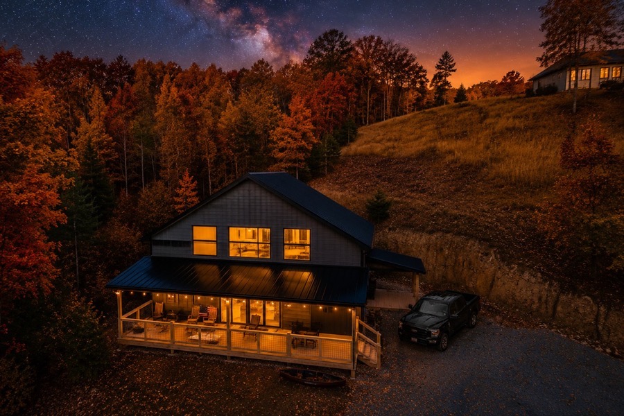 A barndominium above the treeline at sunset